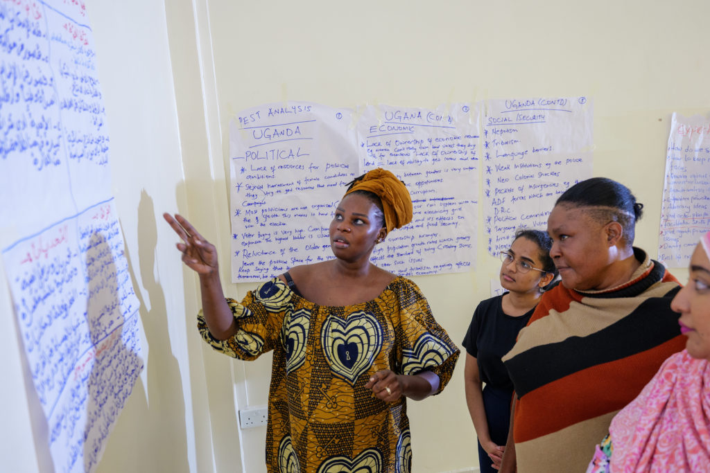 Ayak Chol Deng Alak, Inclusive Peace’s Peace Process Support Advisor, points at handwritten notes on the wall during a women’s coalition workshop on Ugandan political issues.